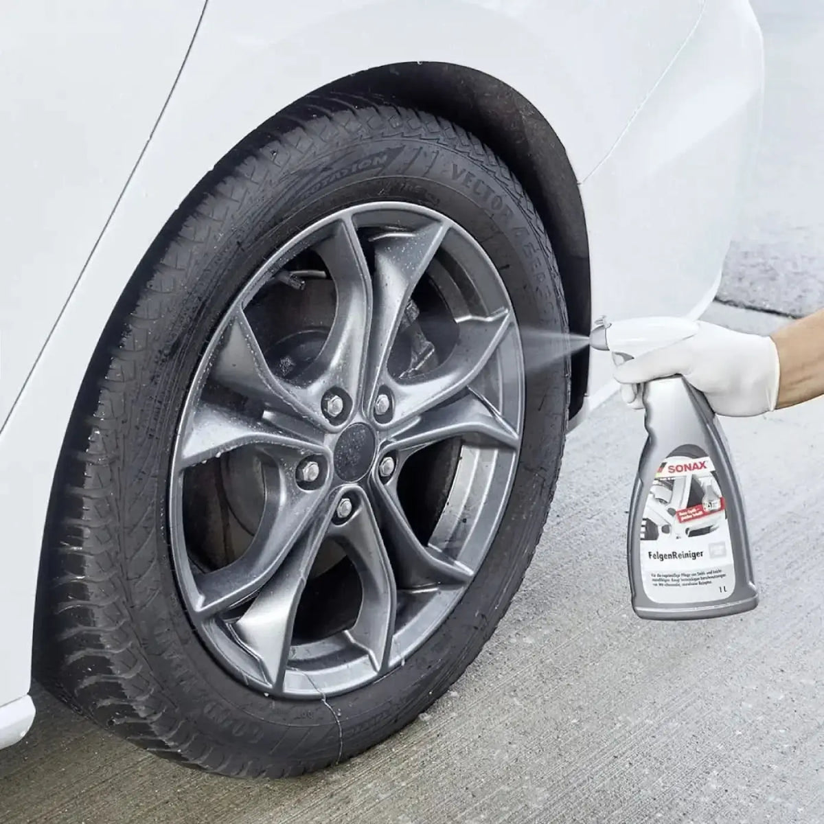 Silberne sonax felgenreiniger sprühflasche wird auf einer auto-legierung felge verwendet