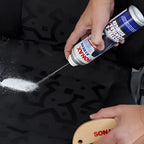 Sonax xtreme polster und alcantara reiniger 400ml in silber und blau wird auf schwarzen autositz gesprüht